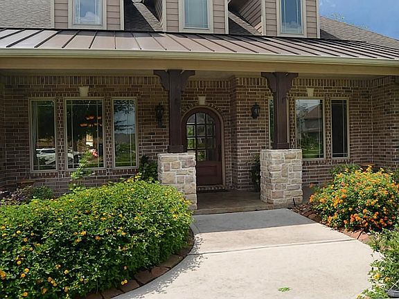The approach along the wide walk reveals colorful landscaping and a covered front Porch accented with corbel's and classic rough sawn beams. Coach lighting casts elegant and inviting illumination.
