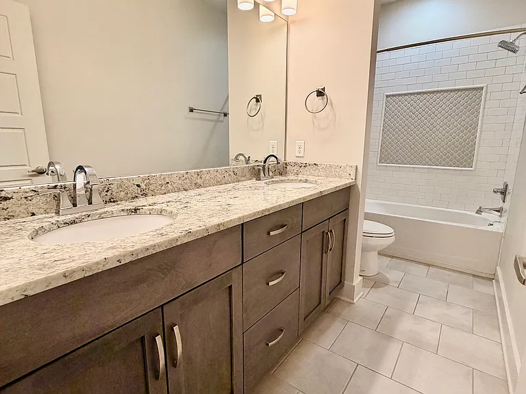 This bathroom has two sinks and is shared between the second and third bedrooms