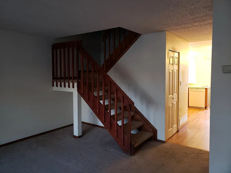 Living room view of stairs to second floor and passage way to kitchen