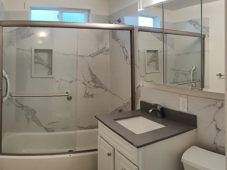bathroom with new marble panel tub, sink and large mirrored vanity