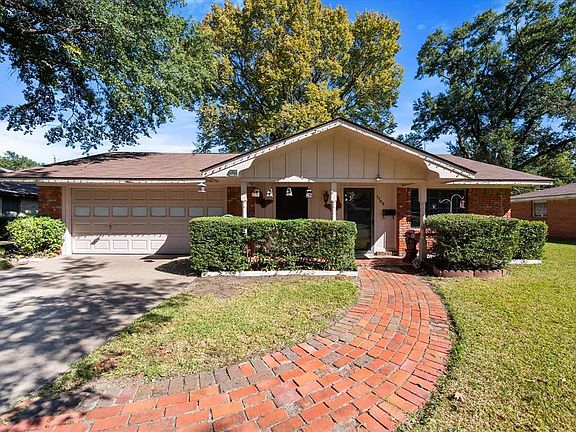 Ranch-style house featuring brick siding, board and batten siding, a front lawn, and driveway