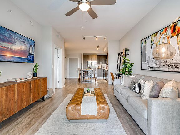 Living Room with Wall-Mounted TV and Entry to Kitchen and Dining Space