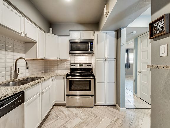 Kitchen with white cabinets, granite countertops, stove, dishwasher and pantry.