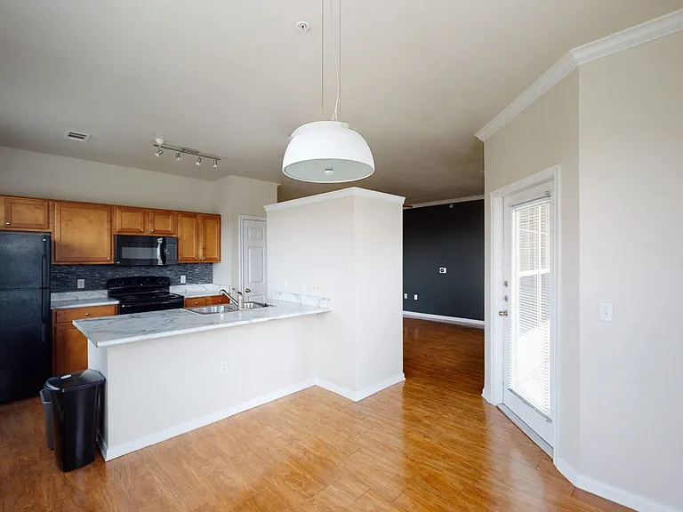 Apartment kitchen, dining and living room with wood-style flooring.