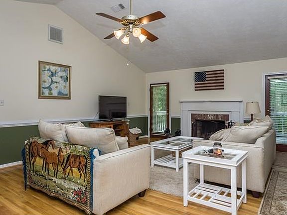 Spacious family room with cathedral ceiling, hardwood floor, ceiling fan, fireplace and two doors to the rear deck.