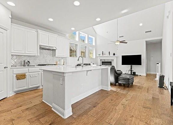 The kitchen boasts white quartz countertops and an open floor plan, seamlessly flowing into the living room with its high ceilings.