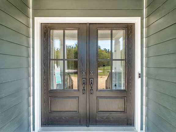 A close-up view of double front doors with glass panes and dark wooden frames, set within a house wi