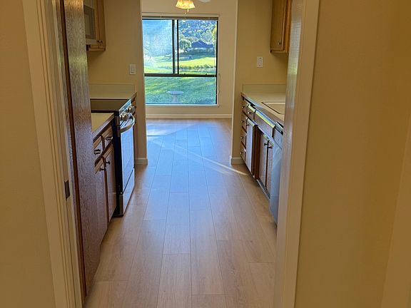 View from front entry through kitchen to breakfast nook with skylight, fan, and pocket door, new laminate floor