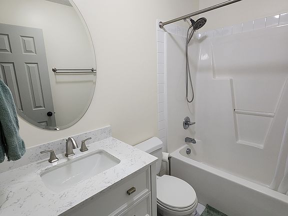 Hall bathroom with updated light, floors, vanity, and showerhead