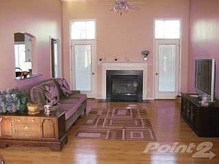 1st view of Great Room with interior lights on with Fireplace & 11' ceilings and hardwood floors