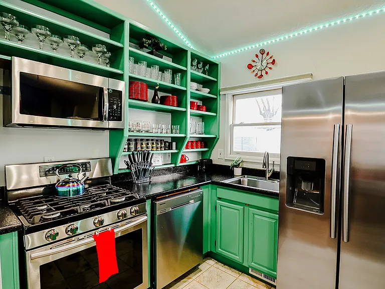 A green and black kitchen fully equipped with complete utensils, blending modern design with practicality for culinary excellence.