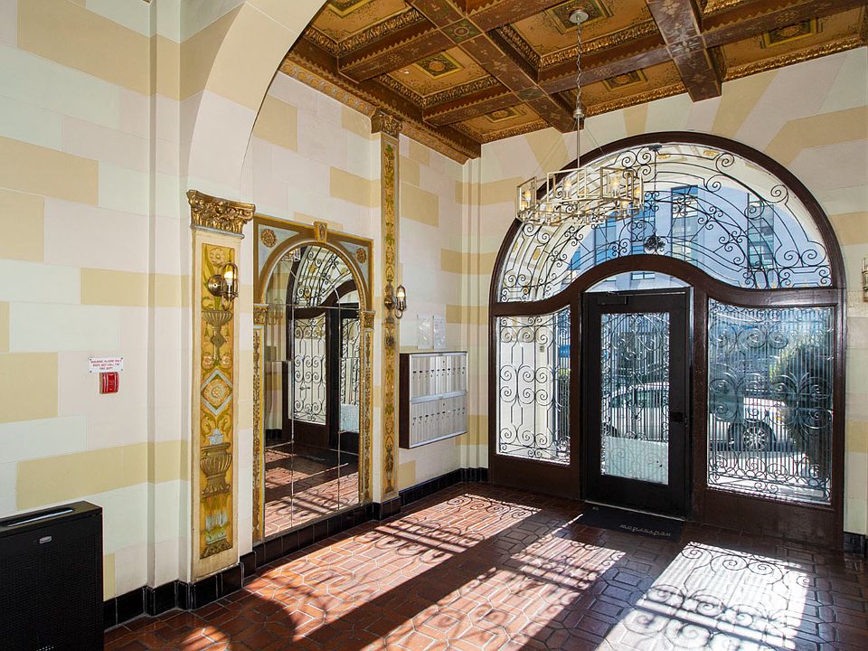 Lobby entrance to a building featuring a large arched door and a large mirror