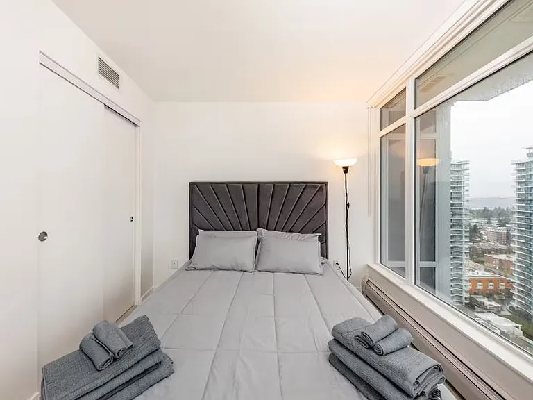 The queen-sized bed is near a large window, offering a scenic overlooking view and plenty of natural light.