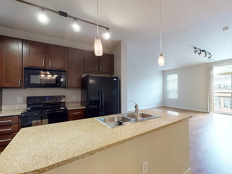 Apartment kitchen with granite countertops and wood-style flooring.