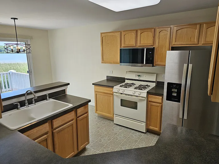 Kitchen with new stainless Microwave and Refrigerator with Ice Maker.