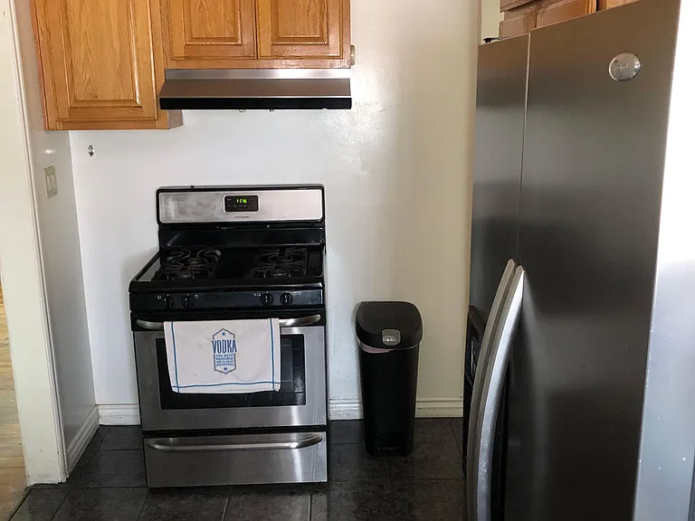 Functional kitchen setup featuring a gas range with vent hood, ample wood cabinetry, and a full-size refrigerator for daily c
