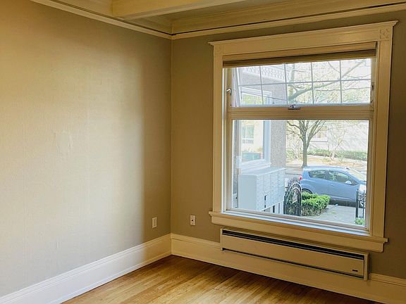 Comfortable bedroom with box beam ceiling, large window, top down/bottom up cellular shades.