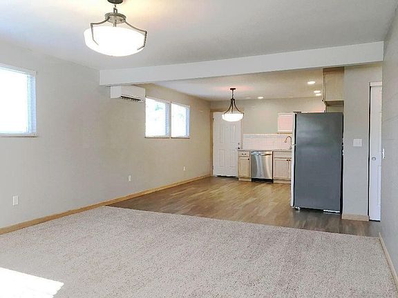 View from the large living room, looking toward the kitchen. Loads of big windows with 2" blinds. Energy efficient mini-split heat pump can be seen next to the far window. A/C and heat!