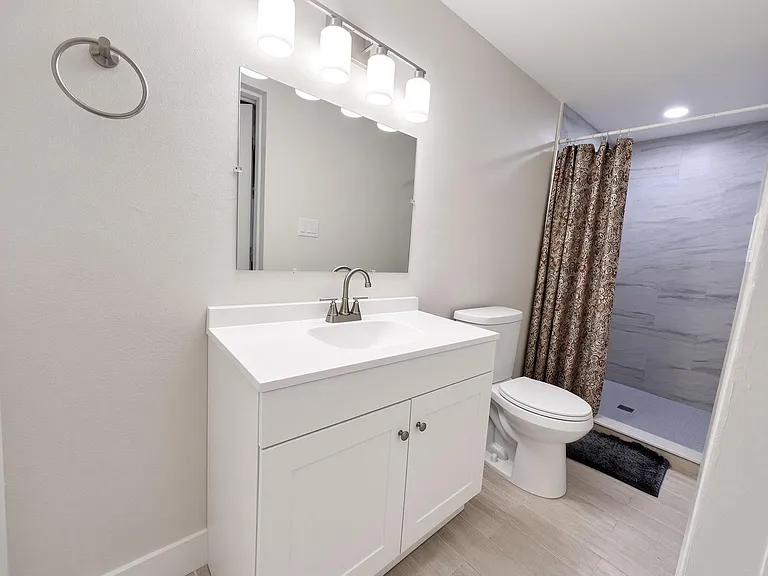 Updated full bath with a single-sink vanity, wide mirror, and walk-in shower with tile surround for easy upkeep.