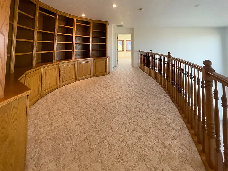 upstairs hallway with gorgeous curved, built in library with storage cabinets.