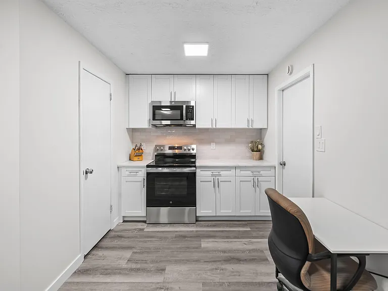 Efficient kitchen with shaker cabinetry, subway-tile backsplash, and stainless range with over-the-range microwave.