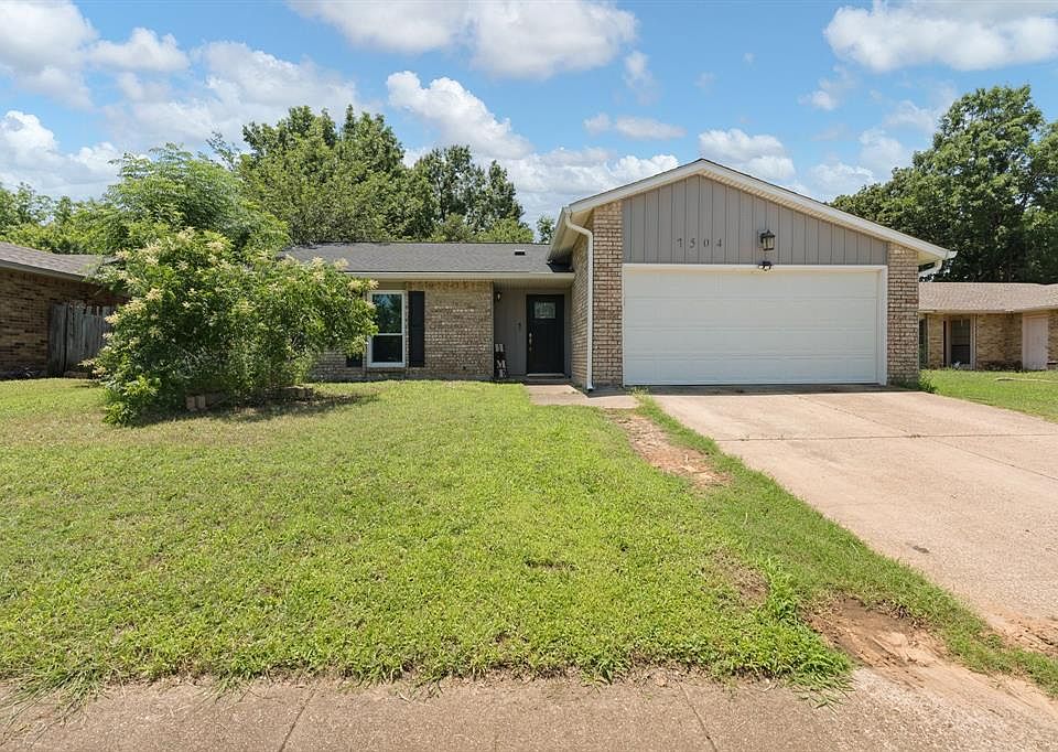 View of front of home with a garage, brick siding, and a front yard