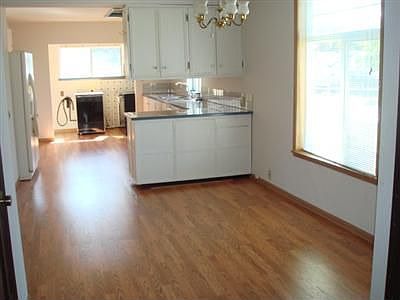 Bright living area is covered in beautiful hardwood. 