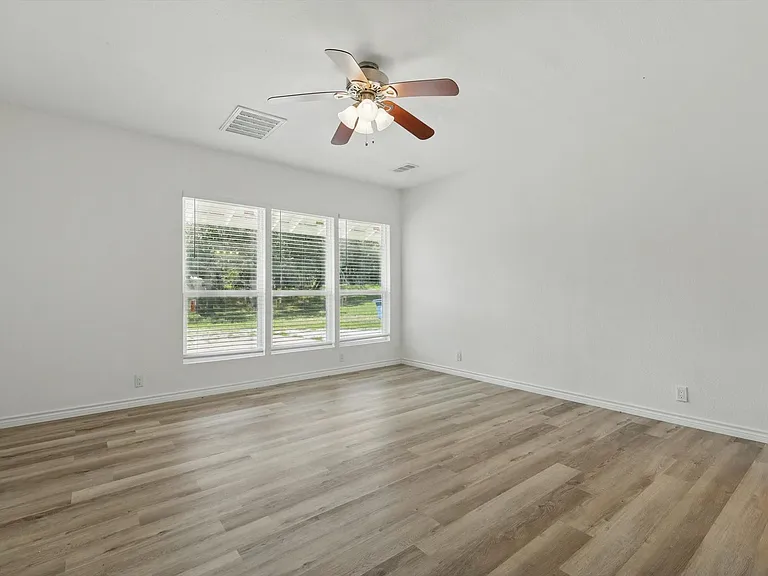 Empty room featuring a ceiling fan, light wood-style floors, and baseboards