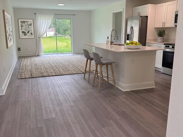 Open-concept kitchen and living area with a large island, stainless appliances, and sliding doors to the backyard.