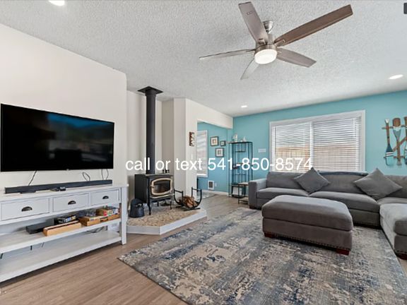 Comfortable large main living room with abundant natural light, Avalon wood stove, large sectional couch and chair.