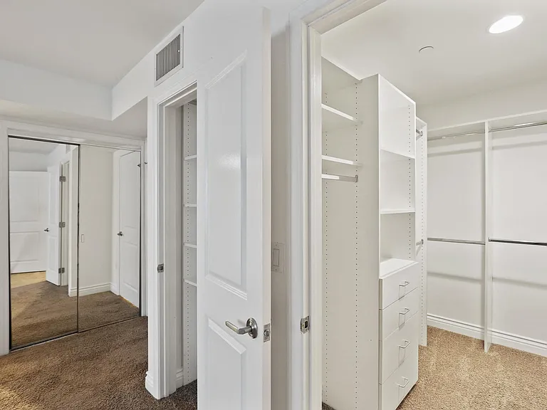 Bedroom with Bathroom, Linen Closet with Shelving, Mirrored Closet, and Walk-In Closet with Built-In Organizers