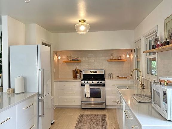 Main level kitchen with soft-close drawers, gas range and oven, discreet dishwasher, garbage disposal (in sink), quartz countertops, and filtered drinking water.