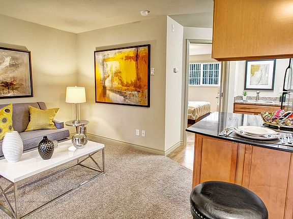 A living room with couch, coffee table, and view into the kitchen