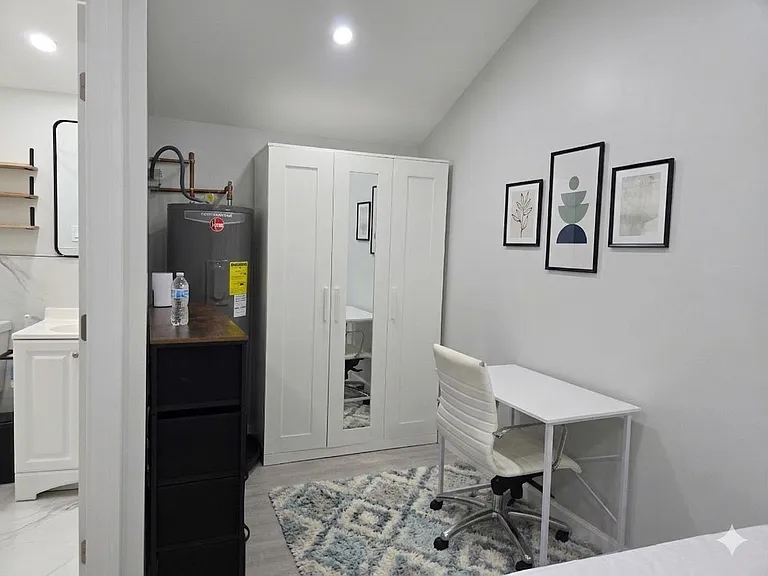 Furnished bedroom with a wardrobe, dedicated desk workspace, and neutral finishes for comfortable everyday living.