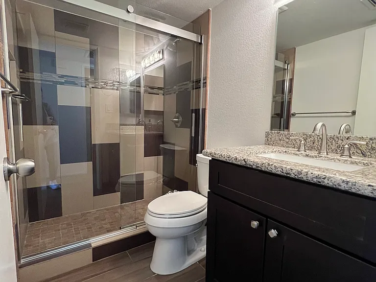 Modern design shower with cool sliding doors, granite-top sink, and toilet with bidet.