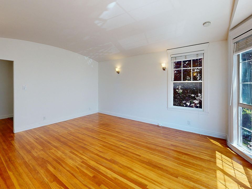 Sunlit living room with a large windows and wood-like floors