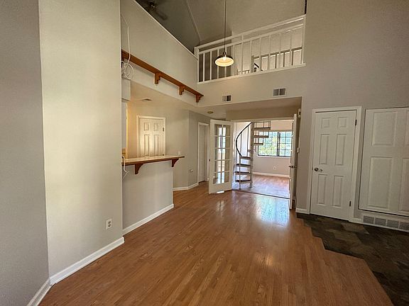 View from main living space - kitchen is on left. Hallway leads back to master bedroom. Second bedroom is straight ahead (double doors open to living room). Spiral staircase goes up to bonus loft/bedroom/home office.