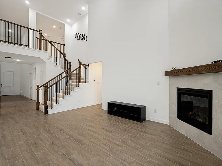 living room features soaring double-height ceilings and a floor-to-ceiling gas fireplace