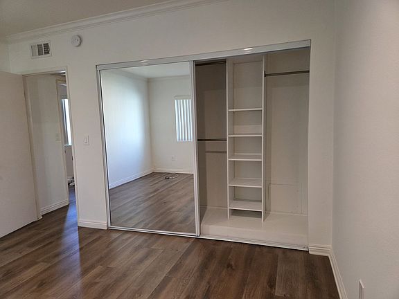 Bedroom with mirrored sliding doors and closet organizers