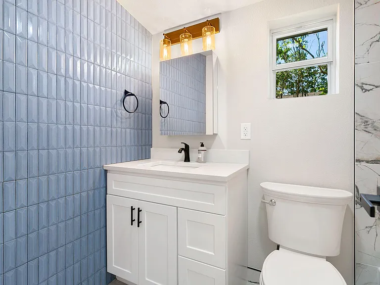 Updated bathroom with a single-sink vanity, framed mirror, modern lighting, and a window for fresh air and daylight.