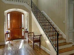 Spacious entry hall is flanked by staircase with wrought iron balusters.