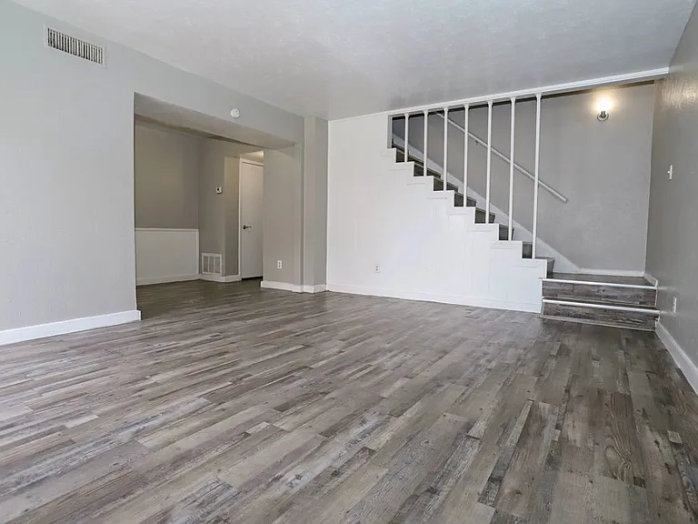 Open-concept living area with wood-style flooring and natural light throughout.