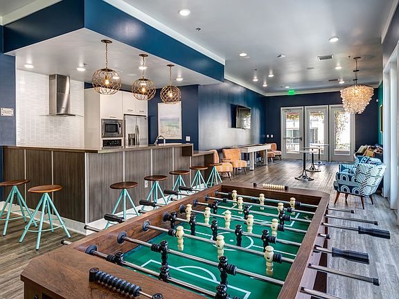Club room with Foosball table, shuffleboard, and full kitchen with bar seating.