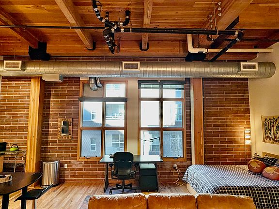 Large windows with privacy shades. Desk (which is electric operated for stand up work) and desk chair. New 
Queen bed. Exposed ductwork and pipes accentuates the loft warehouse look.
