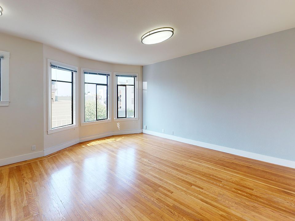 Sunlit living room with a large window and wood-like flooring