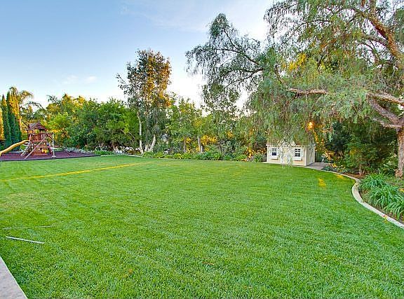 Wide grassy area w/ playhouse & playset