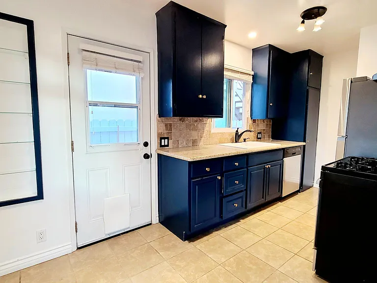 Kitchen has recessed shelves and blue cabinets with gold knobs