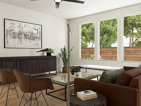 A modern and cozy living room with a large window overlooking a lush, green outdoor space, featuring