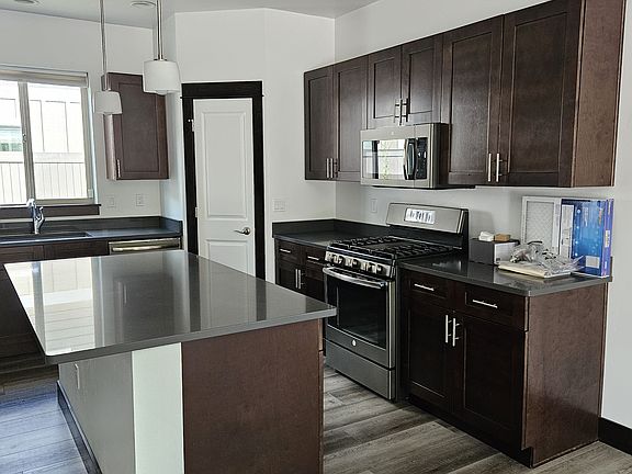 Kitchen with a gas stove, pantry, microwave, island, quartz countertops.