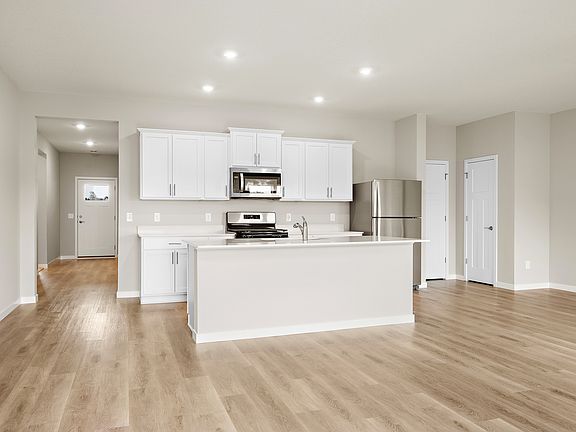 The kitchen has stainless steel appliances and plank flooring.